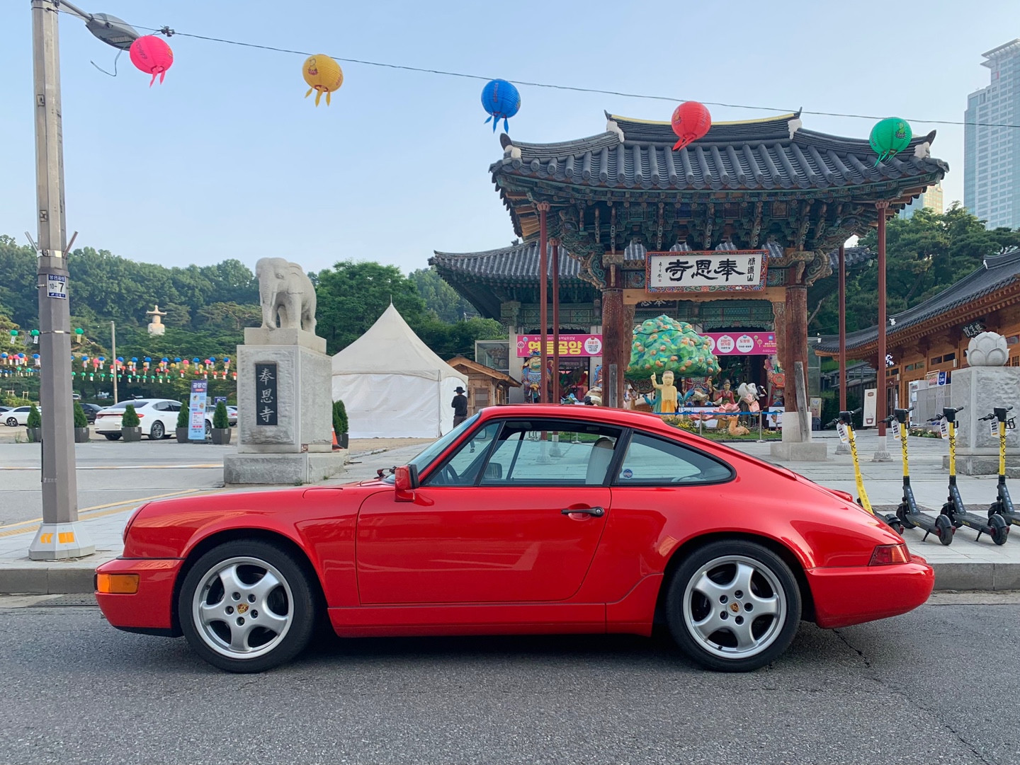 A red 911 in the scenery outside a temple gate.
