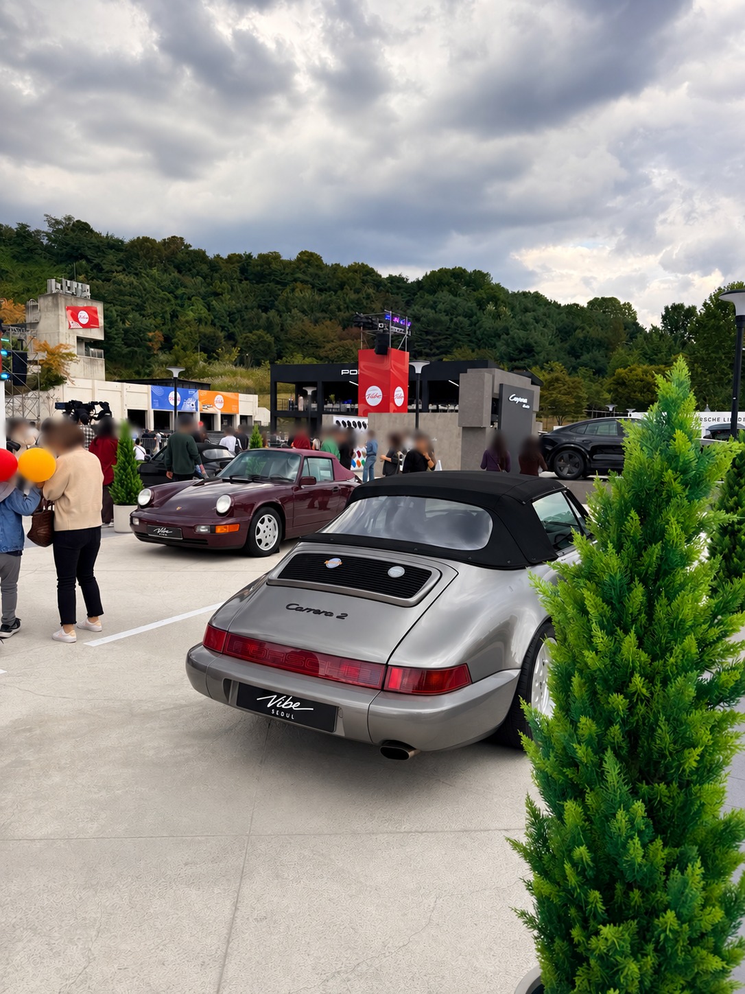 The rear of a silver Carrera 2 Cabriolet. Faces blurred for privacy.