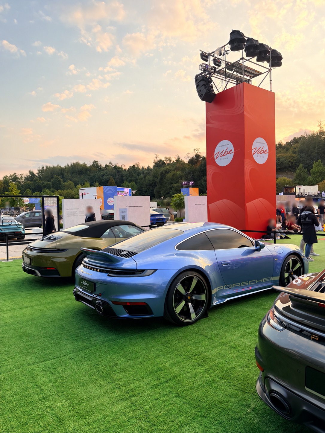 Porsches and the Vibe Seoul tower in the evening light.